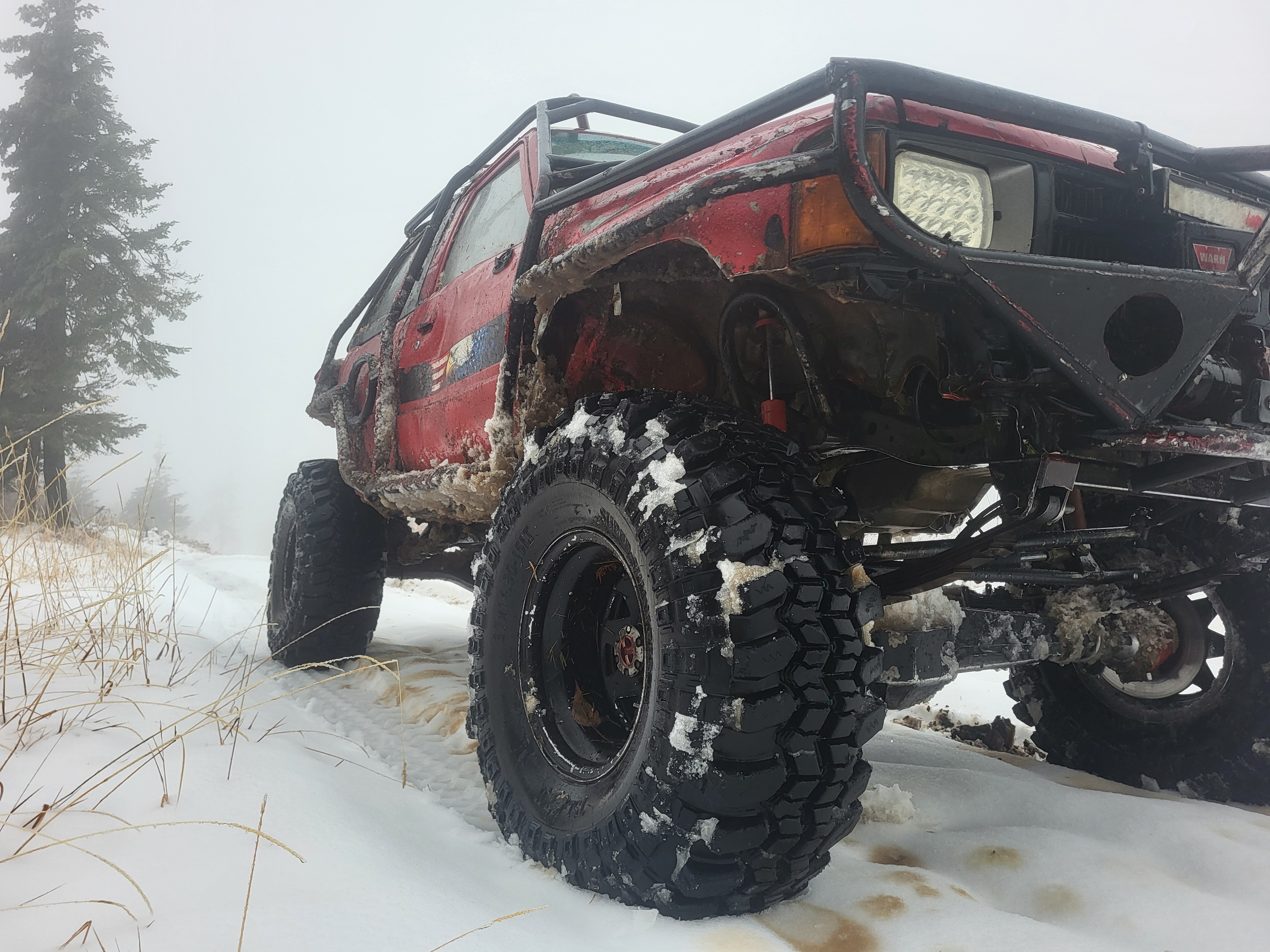 Red 1985 4Runner with exo cage and 37s snow wheeling on a North Idaho ridge